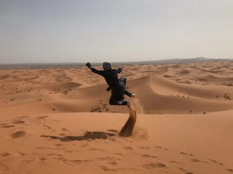 Child jumping in the Sahara dunes on a family trip to Morocco