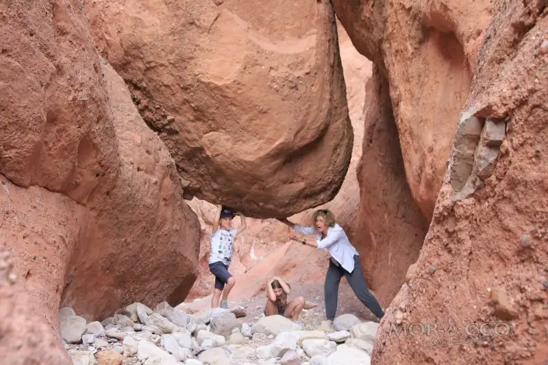 Mother and children playing under a giant rock in a Moroccan gorge